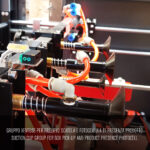 Zbliżenie przemysłowego mechanizmu przyssawkowego z pomarańczowymi rurkami i czujnikami do pobierania pudełek w Automatycznej formierce Speed Former 50 SB XL. Włoskie i angielskie nakładki tekstowe wyjaśniają jego funkcję.