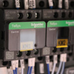 Zbliżenie na dwa przekaźniki sterujące Schneider Electric TeSys, KM1 i KM2, okablowane w panelu elektrycznym - elementy systemu sterowania Automatyczna Formierka Prędkości 50 SB TN HM.