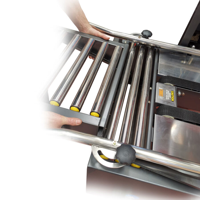 Osoba ustawia metalowe rolki na przenośniku przemysłowym, używając obu rąk, obok półautomatycznej zaklejarki Easy Tape 50 TBB.