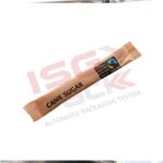 Jednorazowe opakowanie cukru trzcinowego w sztyfcie leży ukośnie na białym tle. Jego brązowe opakowanie, wyprodukowane przy użyciu Pionowa maszyna pakująca Mini Vert 240 PP, posiada również znak certyfikacji Fairtrade.