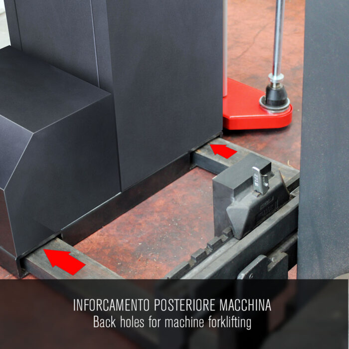 Zbliżenie tylnej części owijarki palet Easy Wrap 2000 A RC pokazuje dwa otwory na wózki widłowe, jeden z zębem wózka widłowego. Czerwone strzałki oznaczają otwory. Nakładka tekstowa: Tylne otwory dla wózków widłowych.