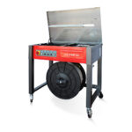 Półautomatyczna bandownica stołowa Eco Strap 501 ma otwartą górę, przyciski sterujące, dużą czarną rolkę do taśmowania zamontowaną pod spodem i jest wyposażona w kółka ułatwiające przemieszczanie.