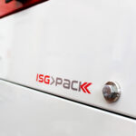 Zbliżenie białej Matic Sealer 65 E automatycznej zgrzewarki kątowej do folii z czerwono-szarym logo ISG PACK, z metalową śrubą po prawej stronie i częścią czerwonego obiektu na górnej krawędzi.