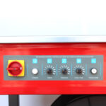 Zbliżenie panelu sterowania na Półautomatyczna bandownica stołowa Eco Strap 501 z oznaczonymi przyciskami i pokrętłami zasilania, timera, napięcia, czasu chłodzenia, podawania / powrotu do domu oraz dużym żółto-czerwonym przełącznikiem obrotowym po lewej stronie.