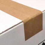 Brązowy pasek taśmy pakowej, naklejony za pomocą Półautomatycznej zaklejarki Easy Paper 50 SB, zakleja krawędź białego kartonowego pudełka, rozciągając się za róg i w dół boku.