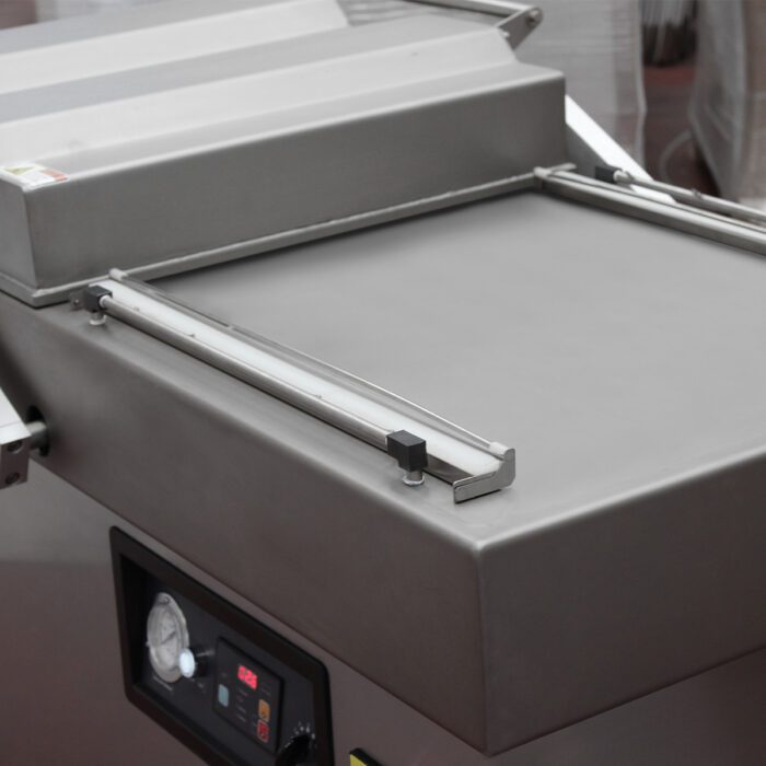 Zbliżenie na Komorową pakowarkę próżniową Ultra Vac 600 SP II, charakteryzującą się konstrukcją ze stali nierdzewnej, cyfrowym panelem sterowania, manometrem, gładką powierzchnią uszczelniającą i trwałymi metalowymi komponentami.