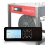 Zbliżenie elektronicznego panelu sterowania z wyświetlaczem i przyciskami, pokazującymi ustawienia i liczby, przed zamazaną Półautomatyczną bandownicą stołową Eco Strap 501 EVO z czerwoną etykietą i szpulą.