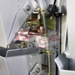 Zbliżenie przemysłowej automatycznej maszyny pakującej z metalowymi sprężynami, dźwigniami, częściami mechanicznymi i wagą wielogłowicową MW 14 do produktów sypkich. Logo i tekst ISCAR AUTOMATIC PACKAGING SYSTEM są nałożone na obraz.