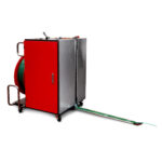 Półautomatyczna bandownica do palet Pallet Strap T150 to czerwono-szara maszyna przemysłowa z kółkami i uchwytami, wydająca zieloną taśmę z wewnętrznej szpuli na podłogę.