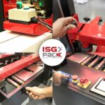 Cztery obrazy przedstawiają dłonie obsługujące elementy sterujące maszyny pakującej, w tym Półautomatyczną zaklejarkę Easy Paper 50 SB. Pośrodku znajduje się logo ISG PACK nad napisem "automatyczny system pakowania".