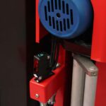 Zbliżenie na czerwoną automatyczną owijarkę Ultra Wrap 2000 BWF z niebieską wentylowaną okrągłą pokrywą, czujnikiem z zielonym wskaźnikiem i metalowymi cylindrycznymi elementami połączonymi czarnymi kablami.