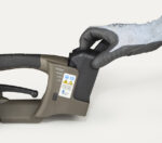 Ręka w rękawiczce wkłada prostokątną baterię do GT-XTREME akumulatorowej wiązarki do taśm PP i PET, z etykietami ostrzegawczymi widocznymi na elektronarzędziu.