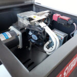 Zbliżenie na wewnętrzne elementy mechaniczne i elektroniczne Półautomatycznej bandownicy stołowej Eco Strap 501 C, pokazujące kable, wentylator chłodzący, silnik, metalowe części, widoczne etykiety i złącza. Obszar jest czysty i dobrze zorganizowany.