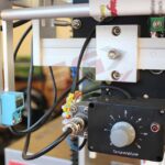 Zbliżenie na Pionową maszynę pakującą Mini Vert 240 PP pokazuje jej wyposażenie elektroniczne, w tym pokrętło regulacji temperatury, przewody, czujnik i części metalowe - kluczowe elementy tej zaawansowanej pionowej maszyny pakującej.