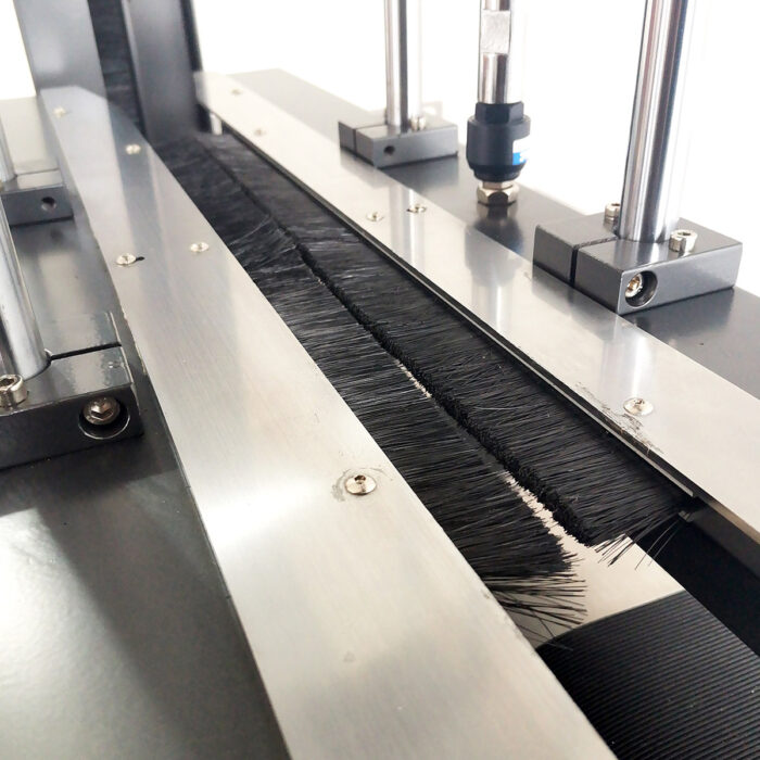 Zbliżenie Bandownicy ramowej wiązarka PP Easy Strap 309P/312P, pokazujące metalowe i plastikowe części z czarnymi szczotkami z włosia i cylindrycznymi prętami, prawdopodobnie część przenośnika przemysłowego lub mechanizmu czyszczącego.