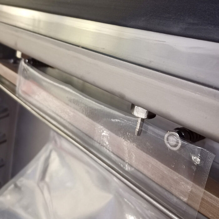 Przezroczysty plastikowy worek jest częściowo umieszczony w zgrzewarce próżniowej Eco Vac 420V TB, z listwą zgrzewającą gotową do dociśnięcia i zgrzania worka.