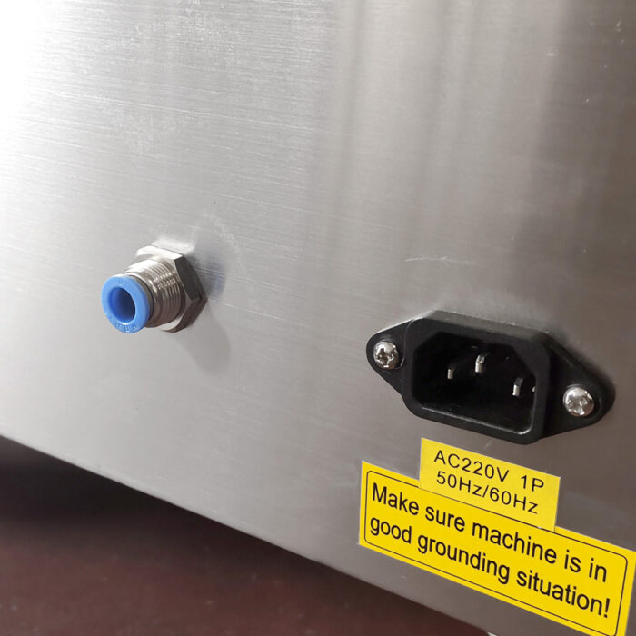 Zbliżenie panelu Komorowej pakowarki próżniowej Eco Vac 420V TB z niebieskim i srebrnym złączem, czarnym gniazdem AC i żółtą etykietą ostrzegawczą zalecającą prawidłowe uziemienie.