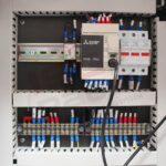 Panel sterowania Pionowa maszyna pakująca Mini Vert 240 PP zawiera oznakowane przewody, sterownik PLC Mitsubishi Electric FX5, wyłączniki i listwy zaciskowe uporządkowane w metalowej obudowie.