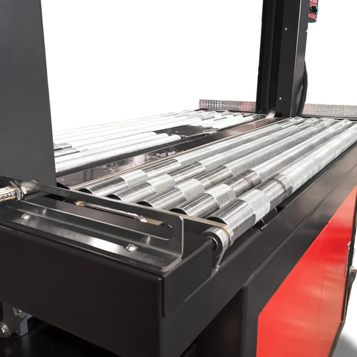 Zbliżenie metalowego systemu rolek przenośnika w połączeniu z Bandownicą ramową wiązarka PP Speed Strap 505RP/509RP/512RP, pokazującą równoległe cylindryczne rolki na czarno-czerwonej ramie dla wydajnego przenoszenia materiałów.