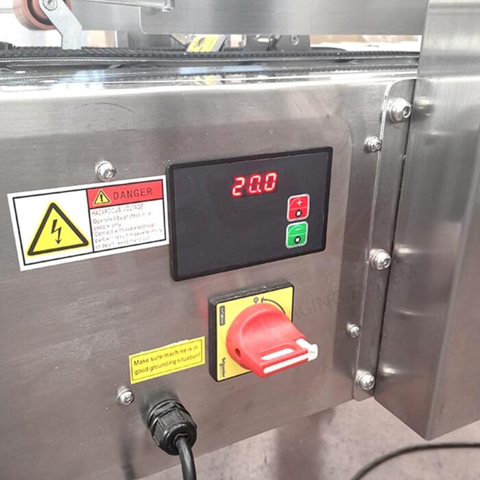 Zbliżenie panelu sterowania Półautomatycznej zaklejarki Eco Tape 50 TBB SS z cyfrowym wyświetlaczem pokazującym 20,0, zielonymi i czerwonymi przyciskami, dużym czerwonym wyłącznikiem zasilania, etykietami ostrzegawczymi i żółtą naklejką ostrzegawczą.