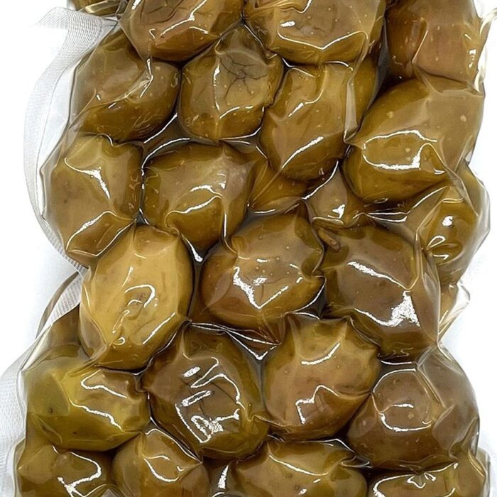Zielone oliwki, błyszczące i świeże z widocznymi zagnieceniami, są zamykane próżniowo w przezroczystej plastikowej torebce za pomocą Komorowej pakowarki próżniowej Eco Vac 420V TB.