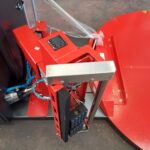 Zbliżenie na Automatyczną owijarkę palet Ultra Wrap 2000 BWF, prezentującą czerwone metalowe i plastikowe części, ekran dotykowy, dźwignie, okablowanie i okrągłą platformę po prawej stronie, a wszystko to umieszczone na betonowej podłodze.