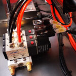 Zbliżenie zaworu pneumatycznego Airtac Model 4V210-08 na Automatycznej Formierce Prędkości 50 SB TN HM, z czerwonymi i pomarańczowymi rurkami, oznaczonymi przewodami Q23-Q25 i metalową powierzchnią w tle.