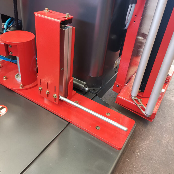 Zbliżenie na Automatyczną owijarkę palet Ultra Wrap 2000 BF, czerwoną maszynę przemysłową z metalowymi prętami i śrubami. Czysta czerwień i metaliczny design podkreślają jej rolę w operacjach pakowania lub przetwarzania.