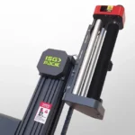 Zbliżenie na Ekonomiczną owijarkę do palet E-wrap 1000A z czarno-zielonym logo ISG PACK, dwiema metalowymi rolkami, etykietą ostrzegawczą i czerwonym elementem u góry na szarym tle.